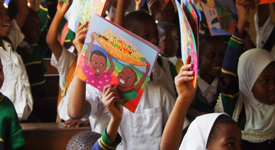 Students raising colorful storybooks during a reading celebration