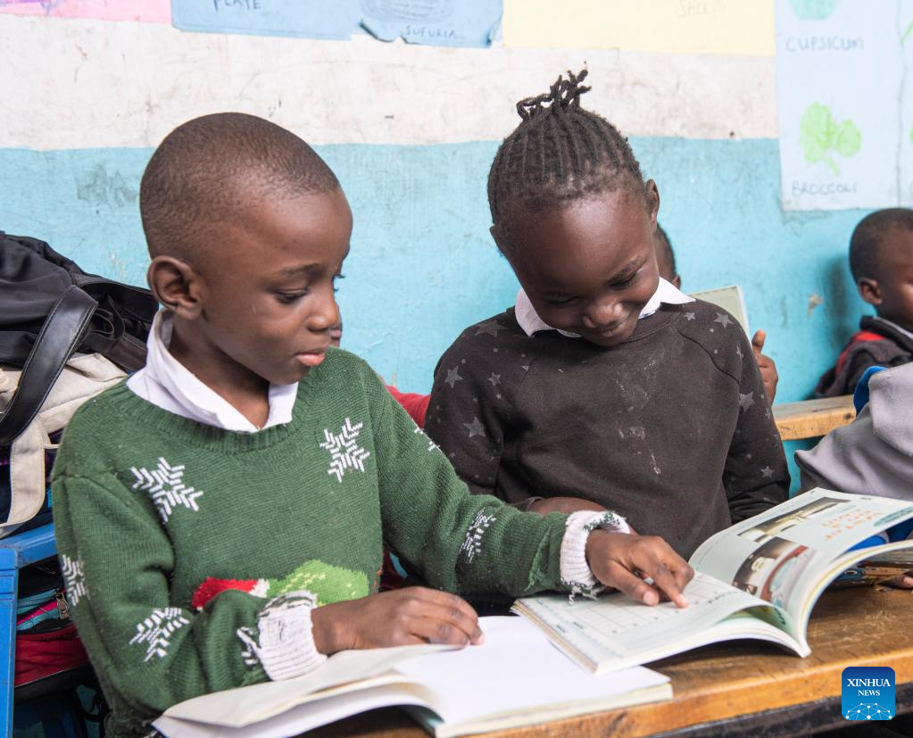 Two children sharing a workbook while seated in class